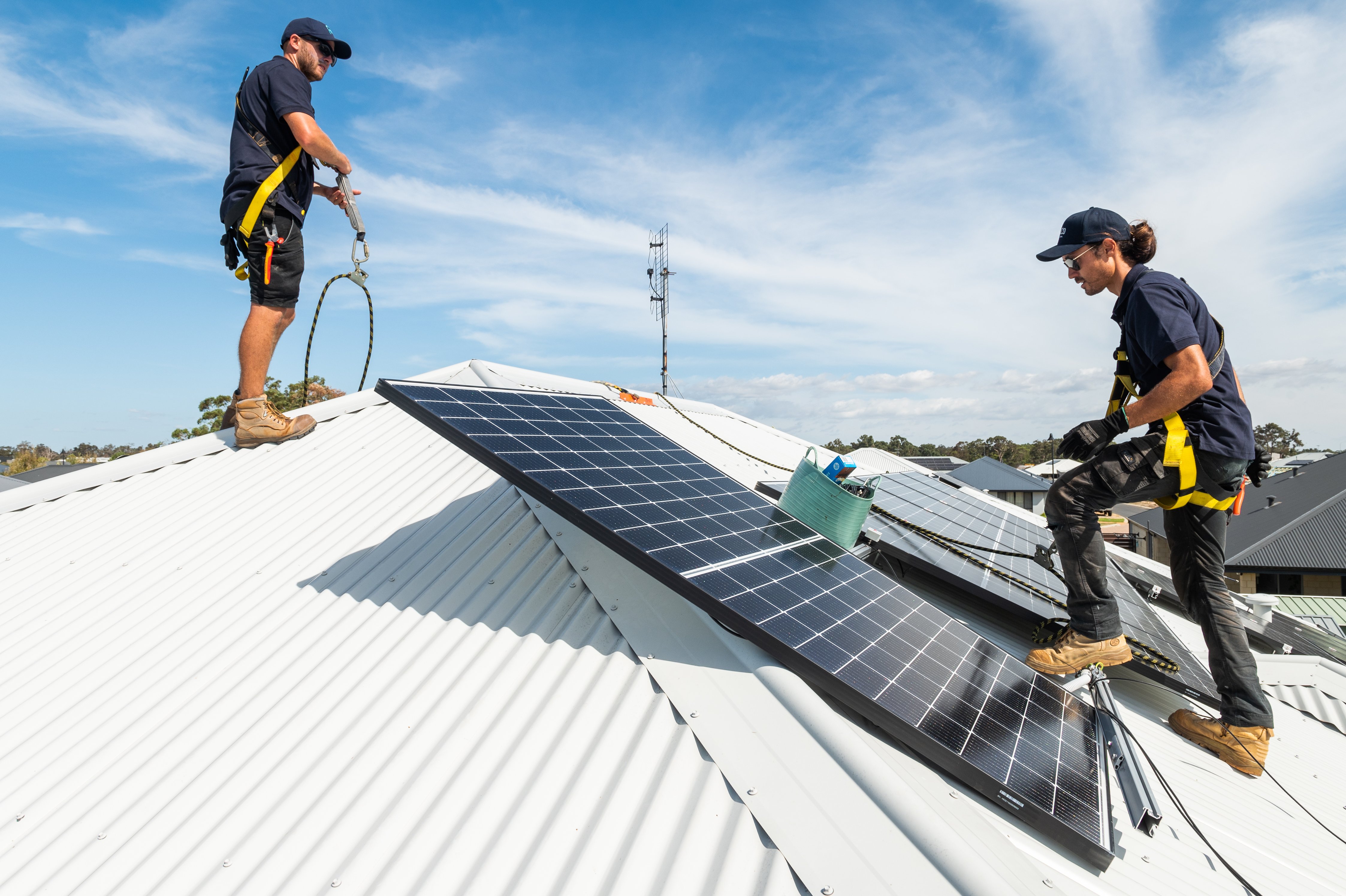The Plico team installing solar panels on a white, corrugated roof