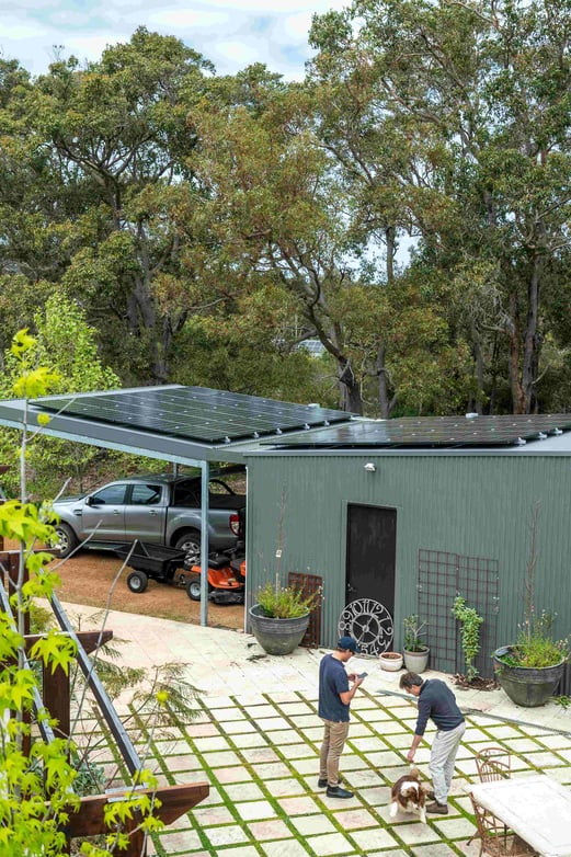 Backyard with two men standing under a roof of newly installed solar panels 