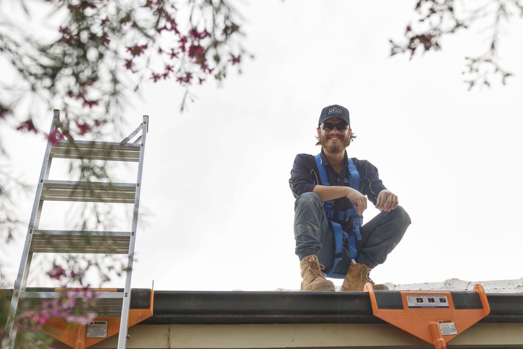 Plico team member installing solar panels on residential home roof