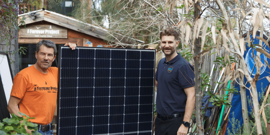 Two men standing next to a solar panel