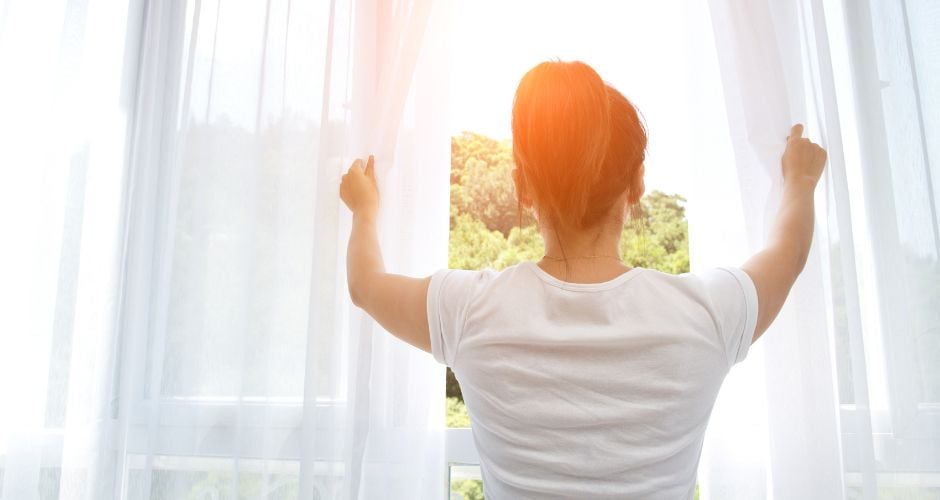 woman opening curtains 