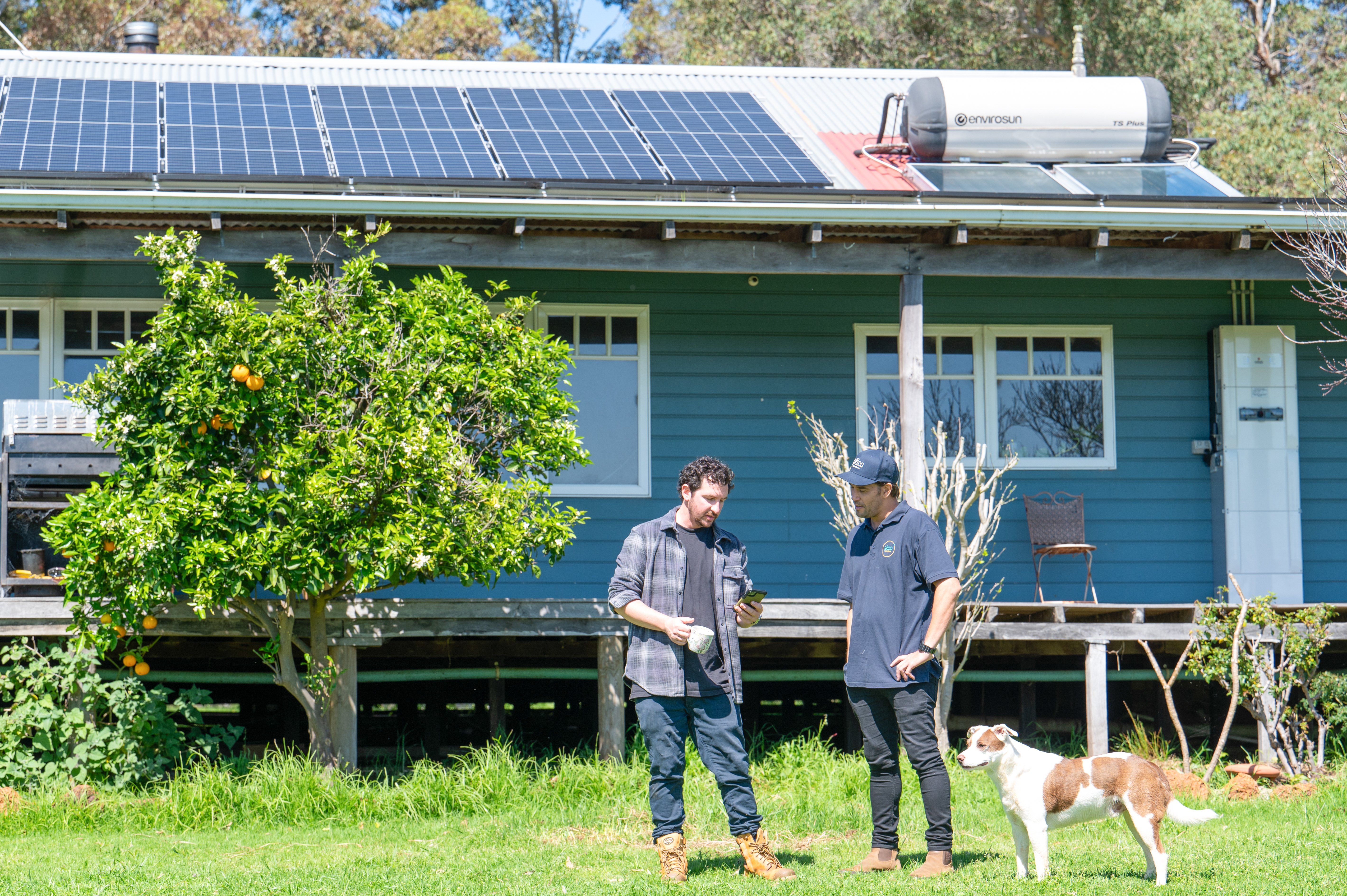 Two men standing in front of a house with a solar panel array on the roof