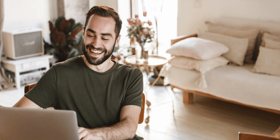 Man in home smiling at computer