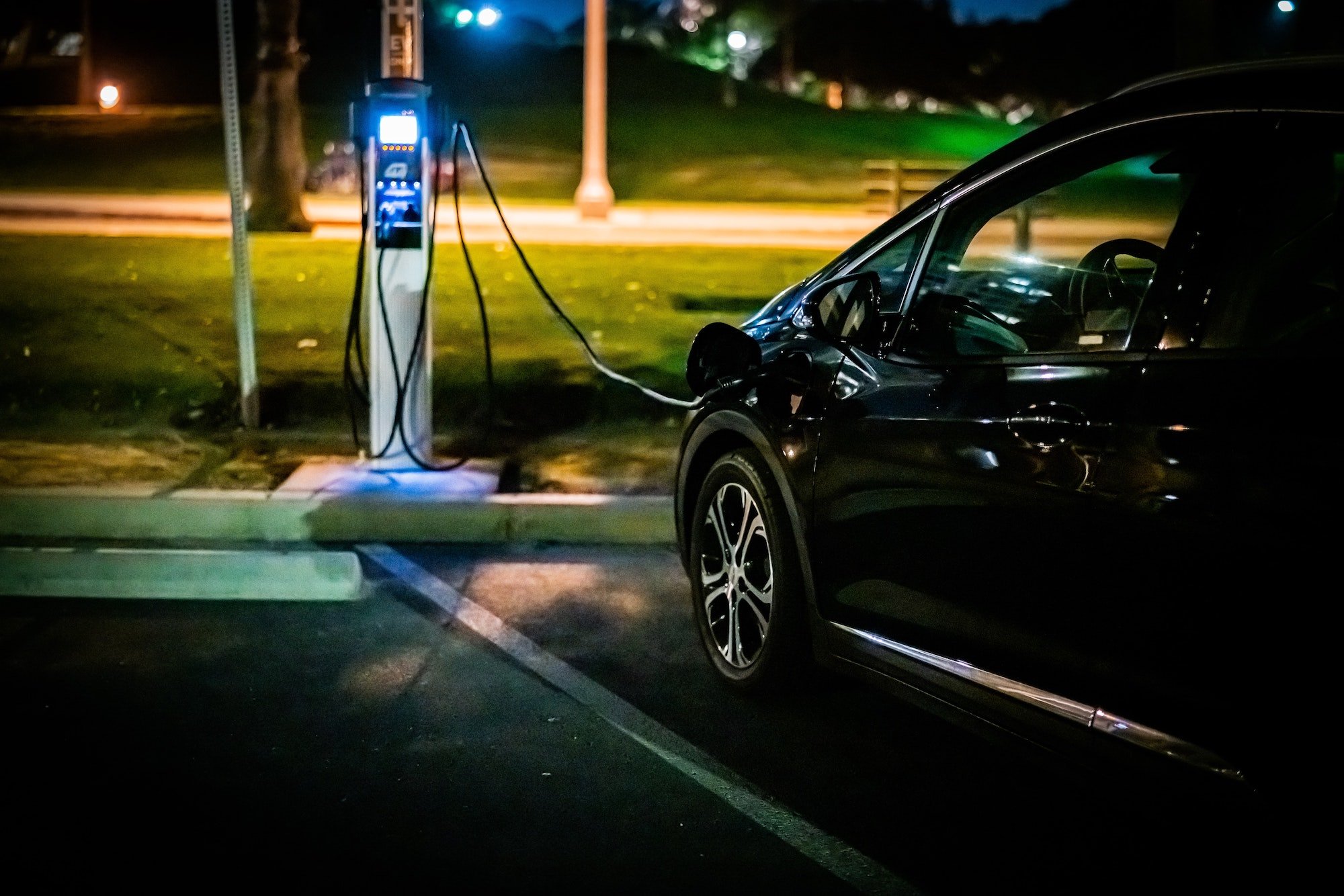 Photo of a black electric vehicle being charged at night by a level 3 public charger