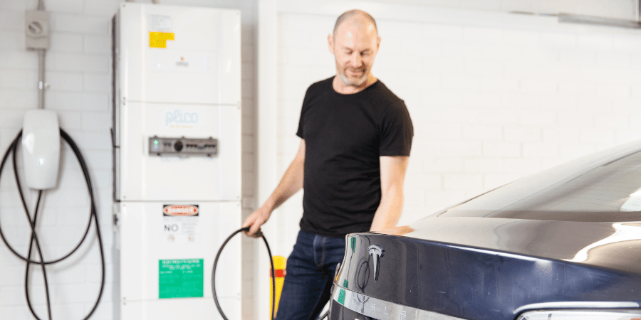 man charging electric vehicle in garage