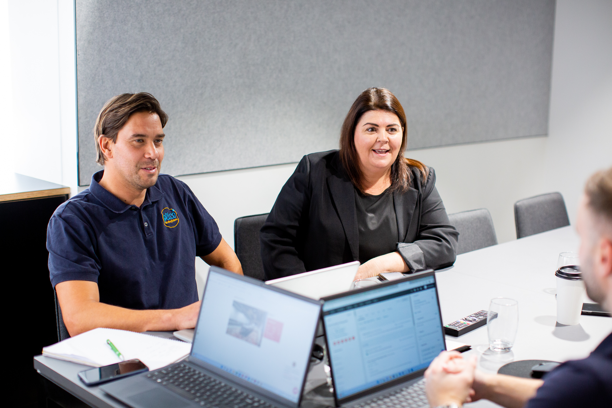 Photo of three Plico team members talking in a boardroom meeting.